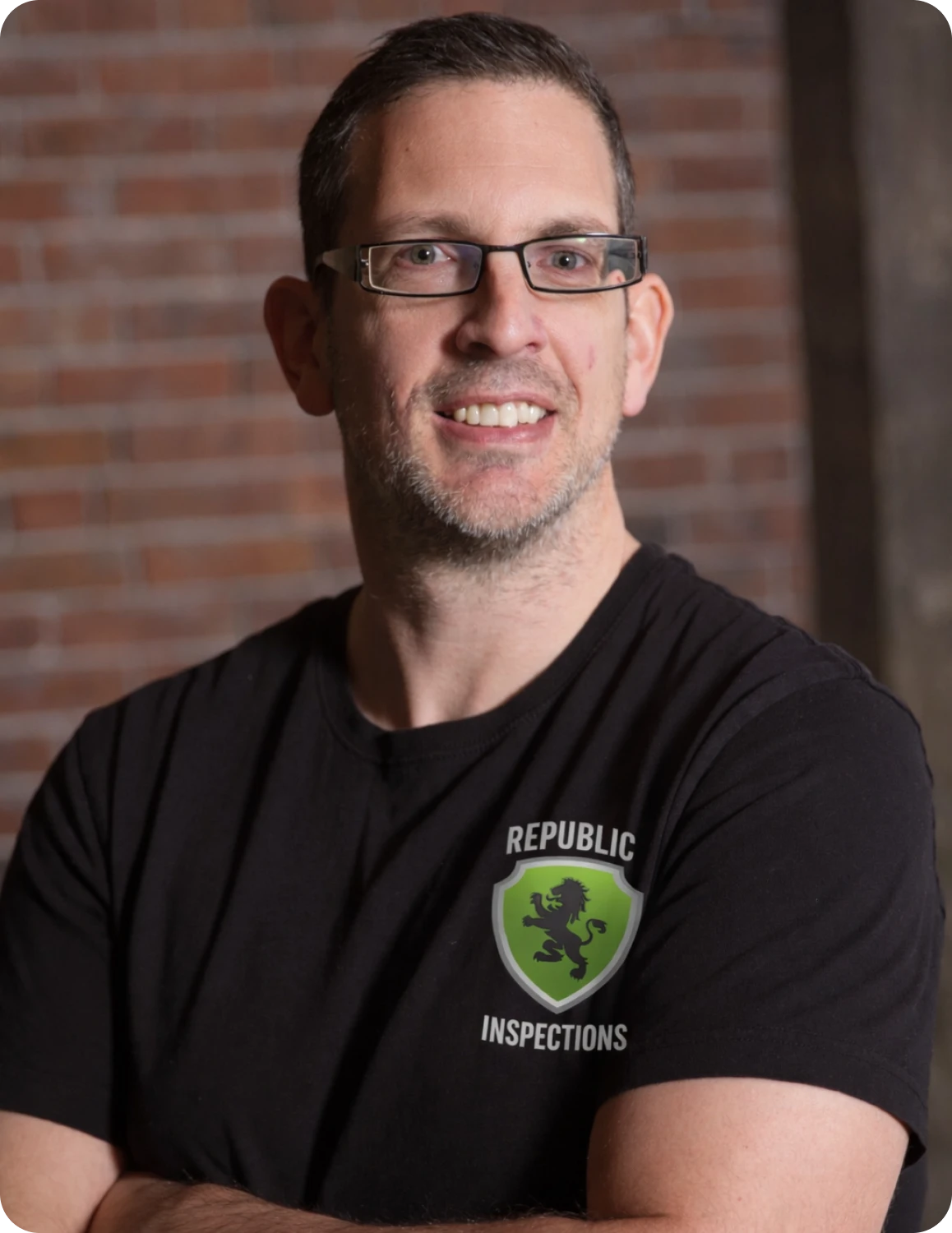 Smiling man in front of brick wall